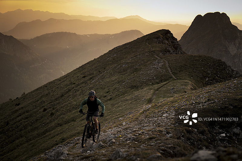 山地车手在日落时骑自行车图片素材