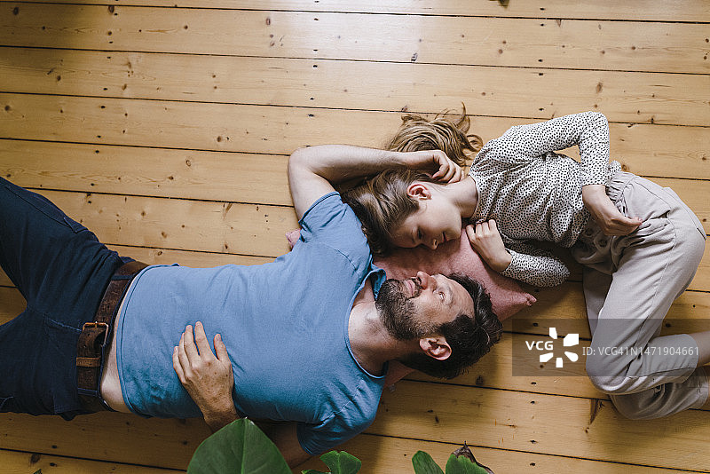 女儿和父亲在家里的地板上躺着图片素材