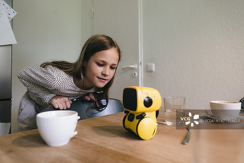 好奇的女孩看着家里的桌子上的机器人模型图片素材