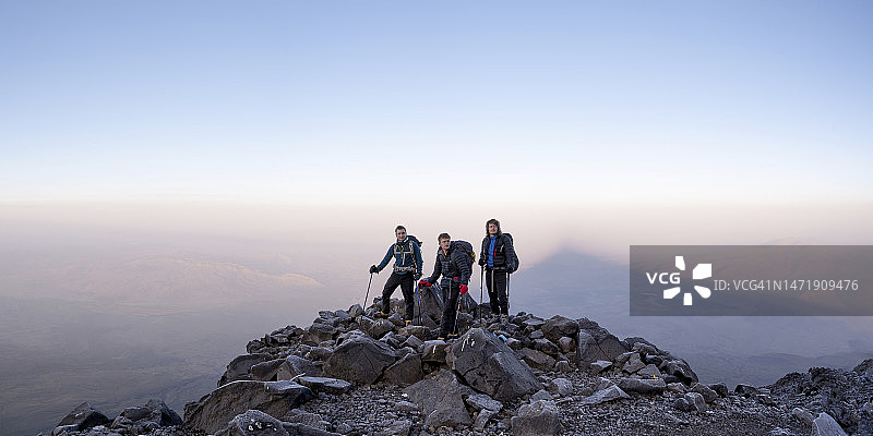 朋友们站在日落时分的天空下的山上图片素材
