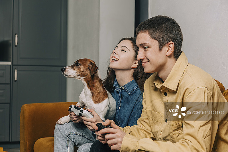 青少年情侣和狗狗在家玩游戏图片素材