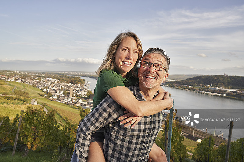 快乐的中年男子在阳光明媚的日子里背着女人图片素材