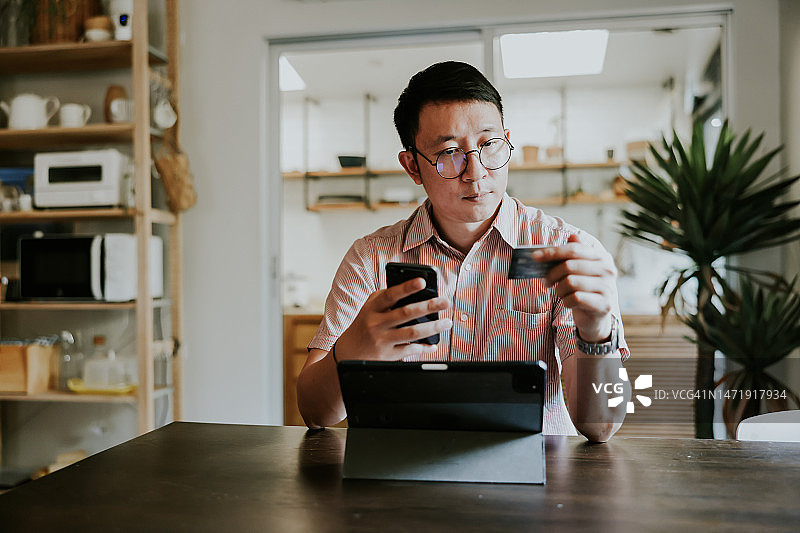 亚洲男子使用手机银行支付信用卡账单图片素材