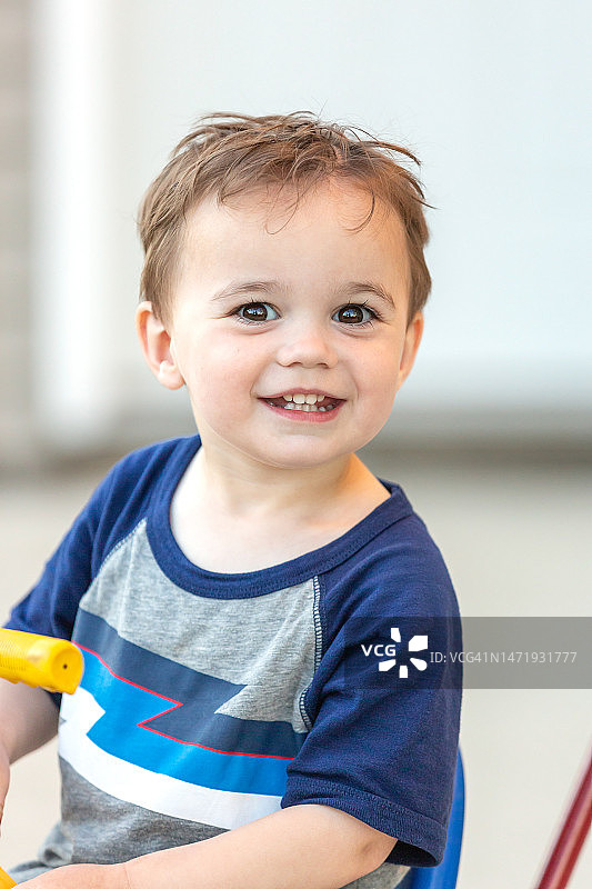 男孩骑着三轮车对着镜头微笑图片素材