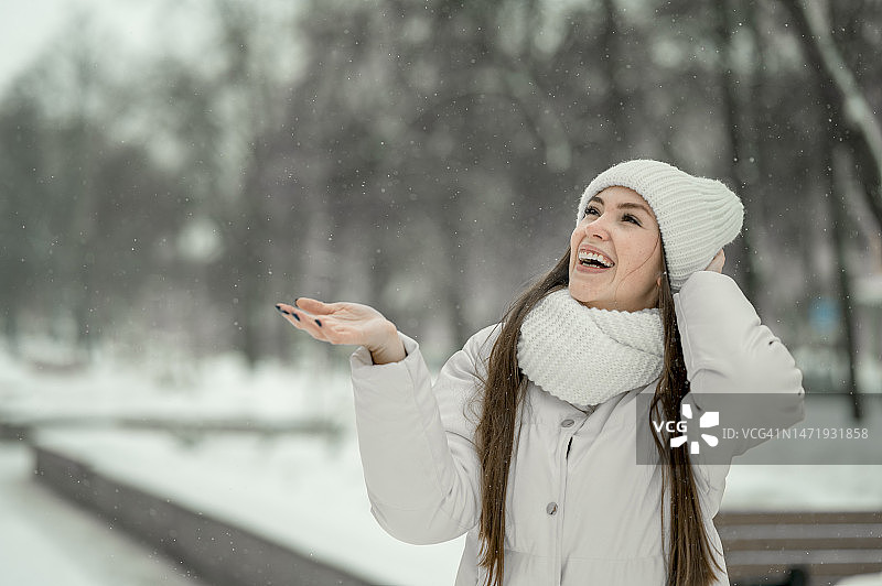 快乐的女人戴着针织帽欣赏雪景图片素材