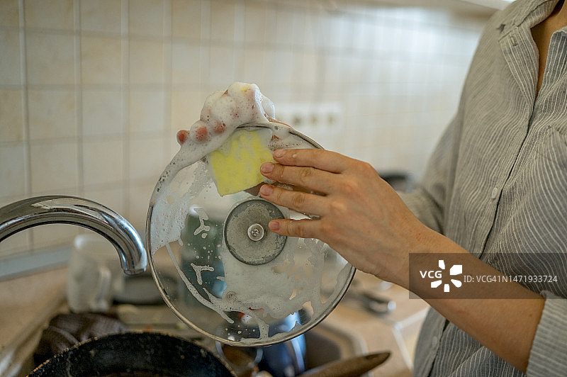 在家中厨房用清洁垫清洗锅盖的女人图片素材