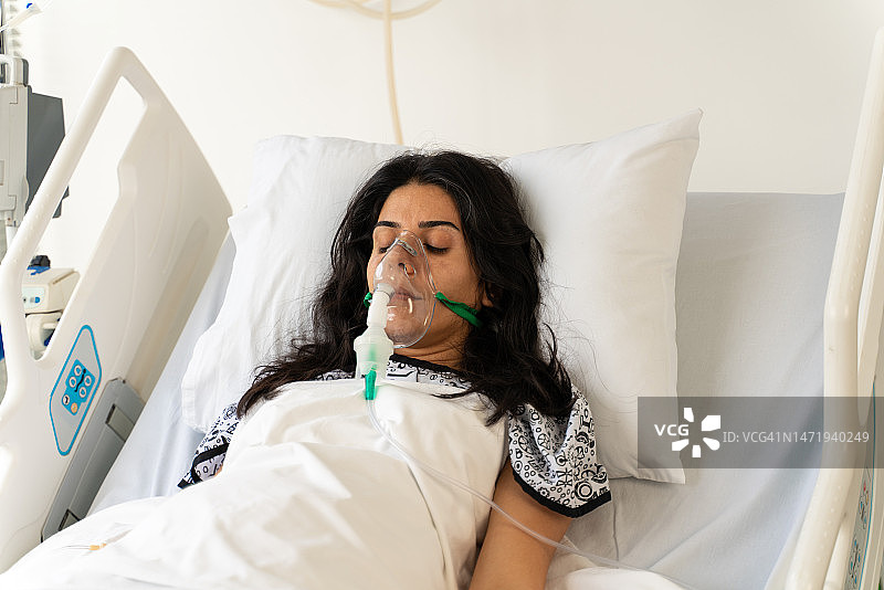 戴呼吸机面罩的女子躺在医院病床上图片素材