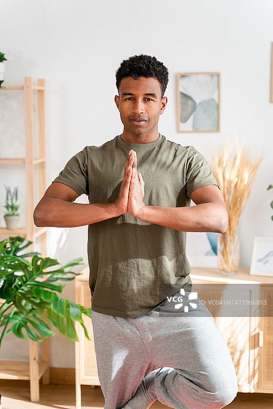 赤脚非洲裔美国男子在客厅垫子上练习瑜伽图片素材