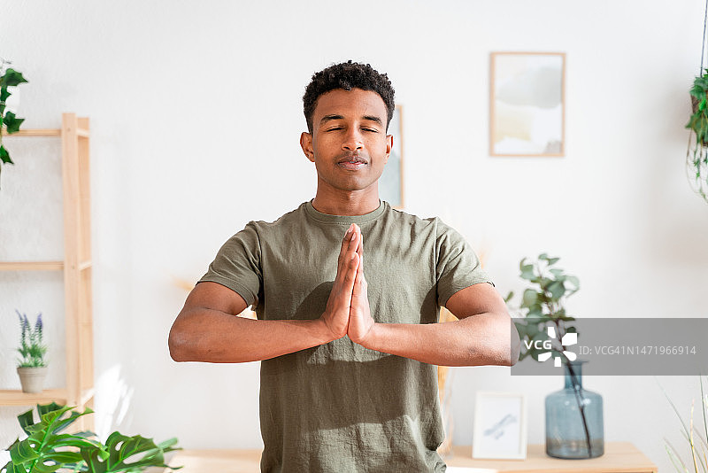 赤脚非洲裔美国男子在客厅垫子上练习瑜伽图片素材