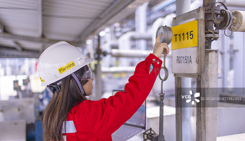 女石化产品检验员在现场检查工业设备图片素材