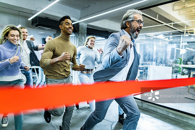 快乐的男商人与同事在办公室运动比赛中冲过终点线时尖叫图片素材