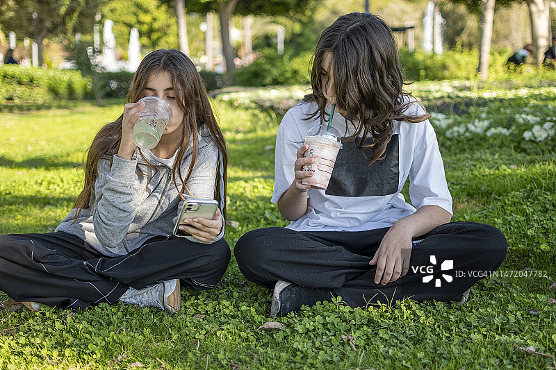 美女在公园用手机喝咖啡图片素材