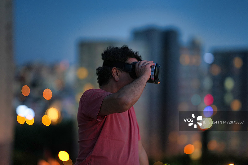 戴VR头显的男人，背景是城市灯光图片素材