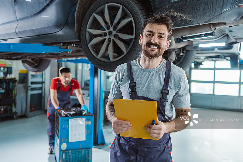 在汽车修理店里微笑的技术员肖像图片素材