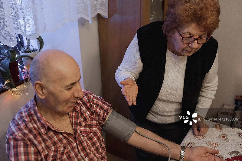 忧虑的妻子查看丈夫血压图片素材