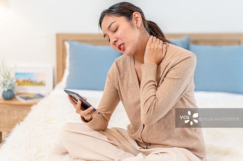 女人一边忍受颈椎疼痛一边使用手机图片素材