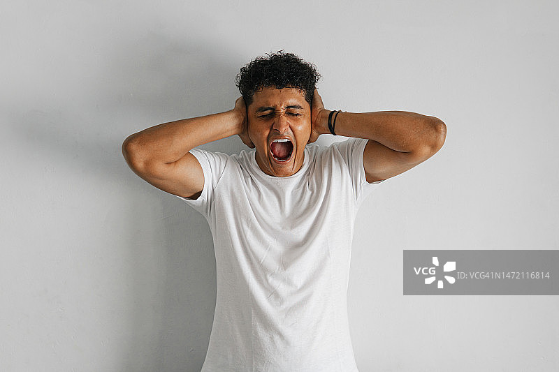 焦虑和沮丧的概念：欣快与愤怒的男人捂住耳朵图片素材