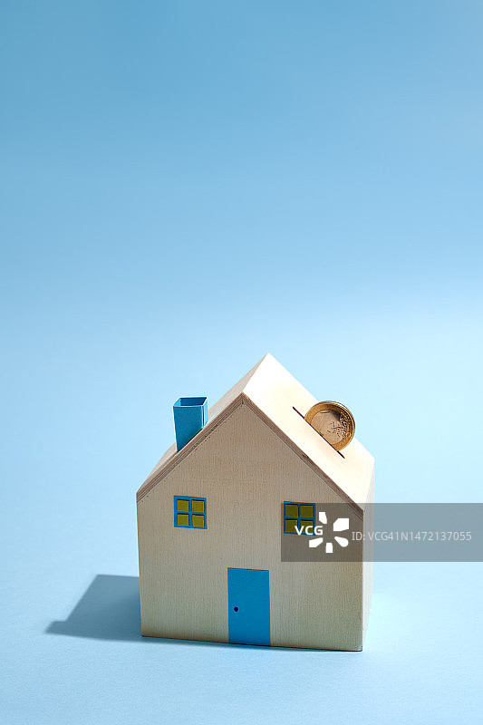 房屋形状的储蓄罐，插槽里有一枚欧元硬币图片素材