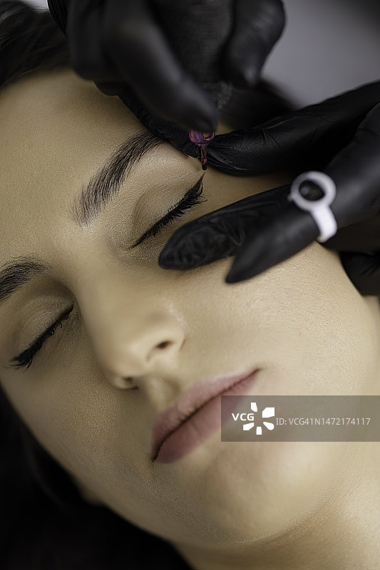 化妆师在美容院进行永久性眼妆图片素材