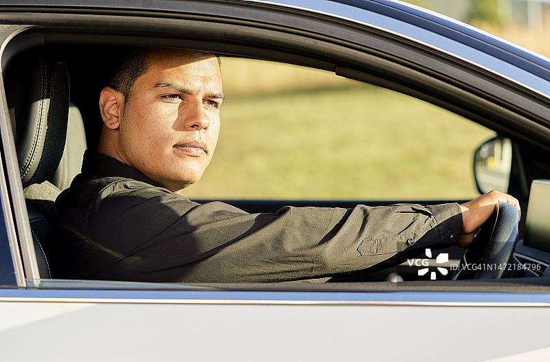 在车内穿着黑色衣服，手臂靠在窗户上，表情严肃地看着镜头的男人图片素材