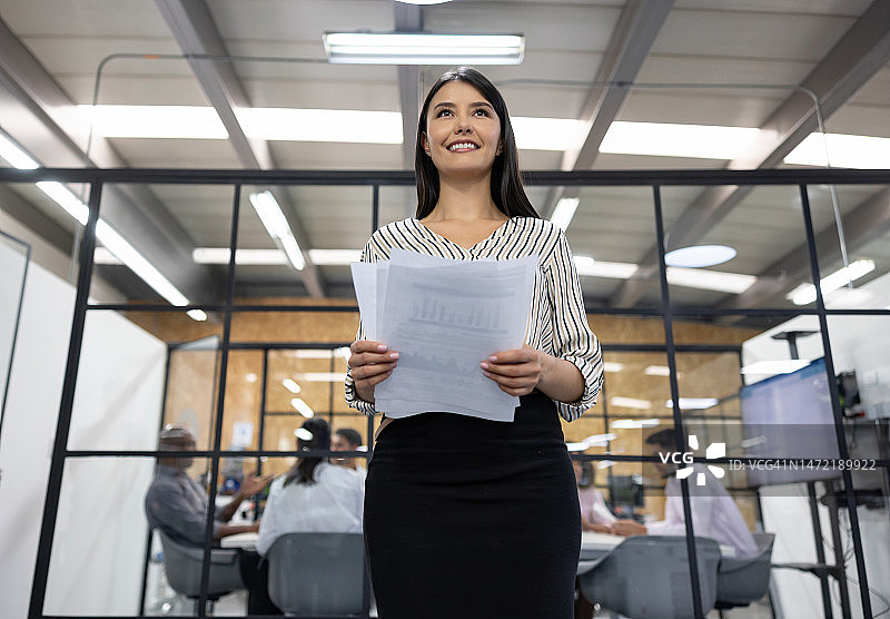 在办公室里拿着文件的商务女人图片素材