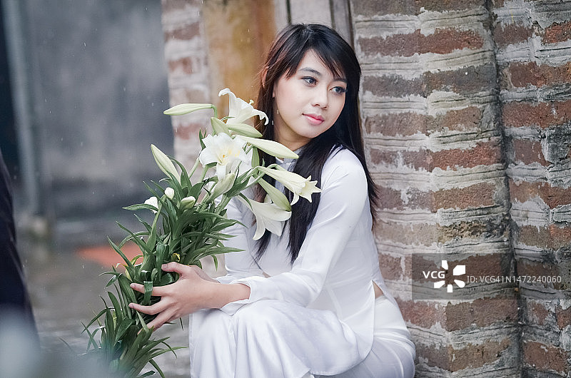 身穿传统奥黛，手持盛开百合花的女孩图片素材