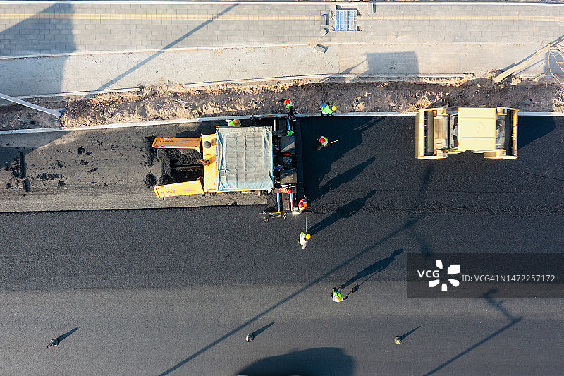 铺路机械和工人在铺设沥青路面图片素材