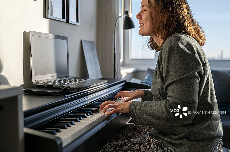 女人在家弹奏数码钢琴图片素材