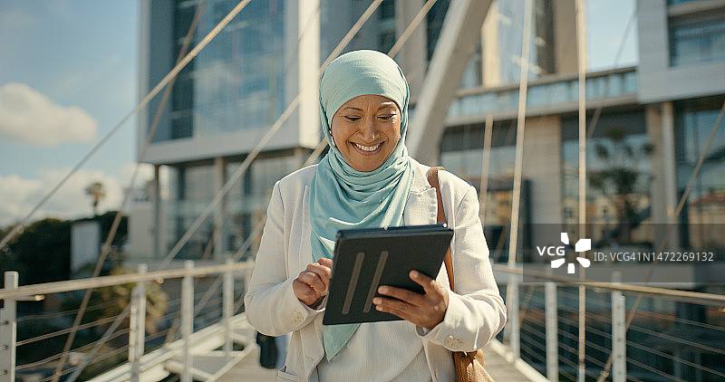 在城市里使用平板电脑微笑的穆斯林妇女，用于商业策略、日程安排或项目计划图片素材