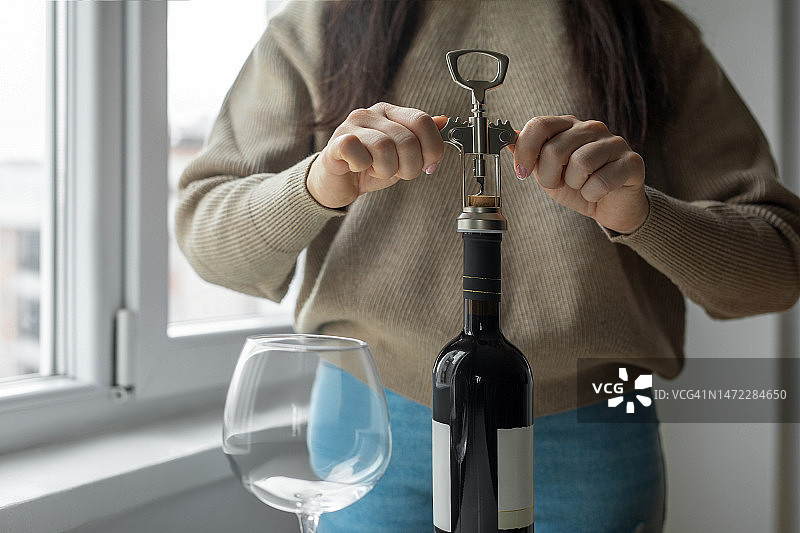 女人用开瓶器打开葡萄酒瓶图片素材