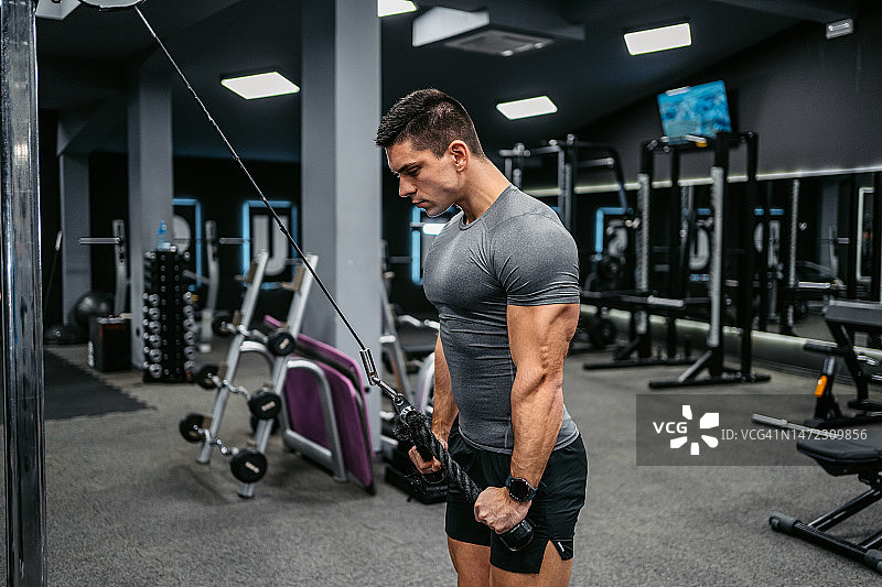 年轻男人在健身房做肱三头肌锻炼图片素材