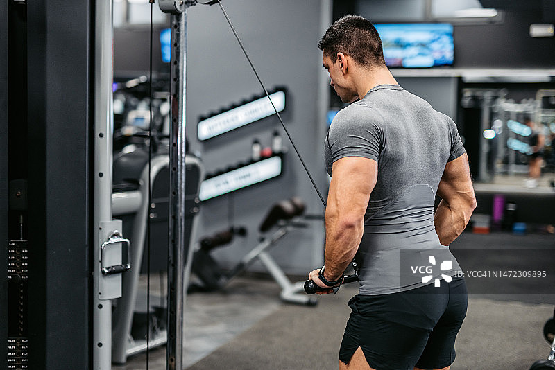 年轻男人在健身房做肱三头肌锻炼图片素材