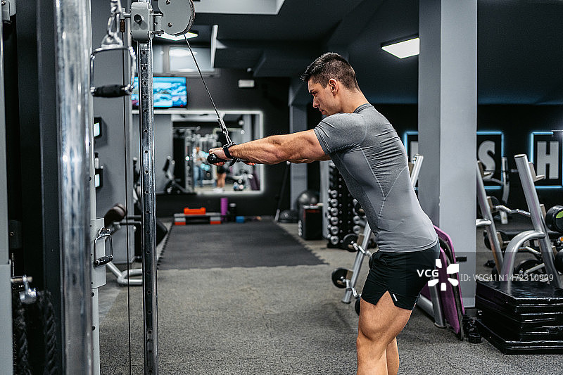 年轻男人在健身房做肱三头肌锻炼图片素材