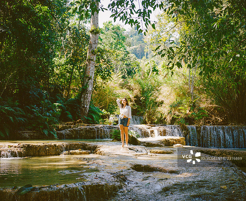 女人站在热带森林的瀑布旁图片素材