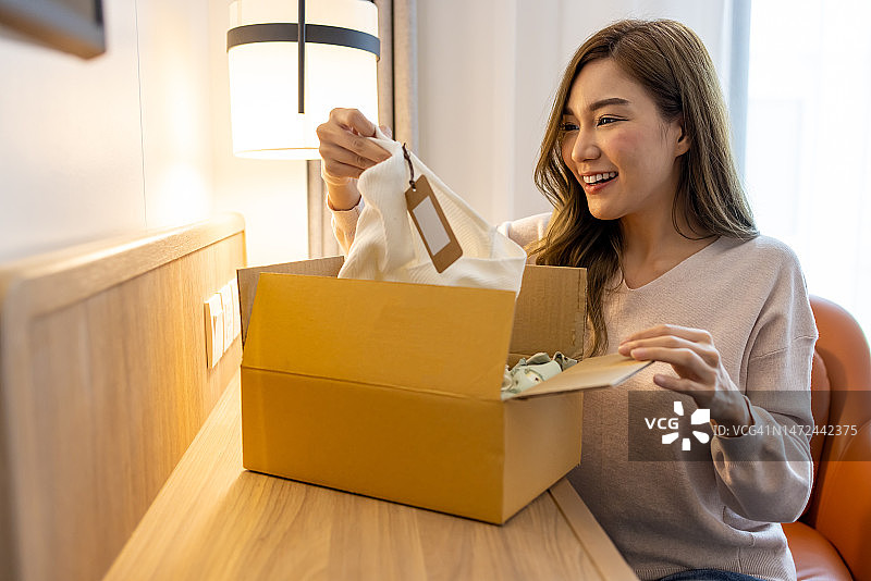 亚洲女性打开网上订购的包裹，接收和拆包在线购买的概念图片素材
