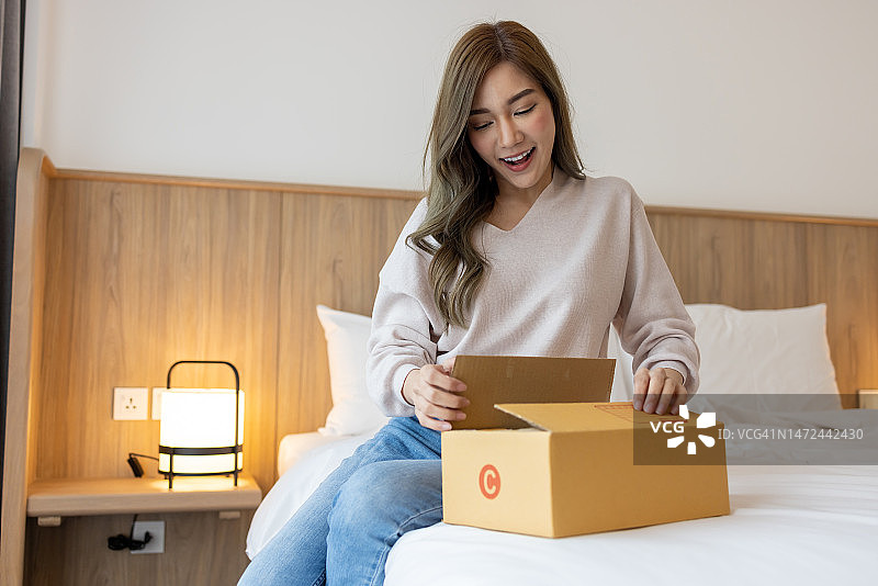 亚洲女人打开网上订购的包裹，接收和拆开网上购买的商品图片素材