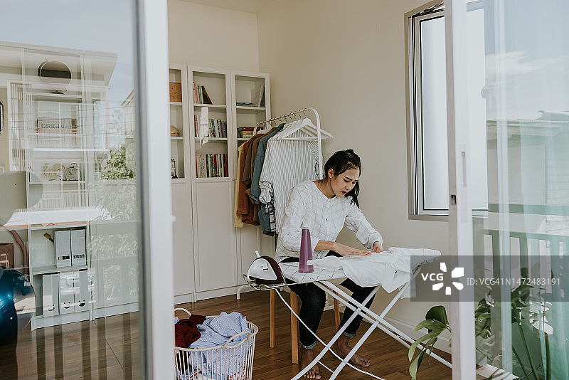 手臂残疾的亚洲女人熨烫衬衫图片素材