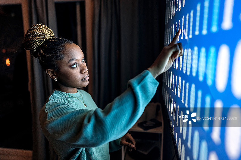 年轻漂亮的女人触摸带有二进制屏幕的数字显示器图片素材