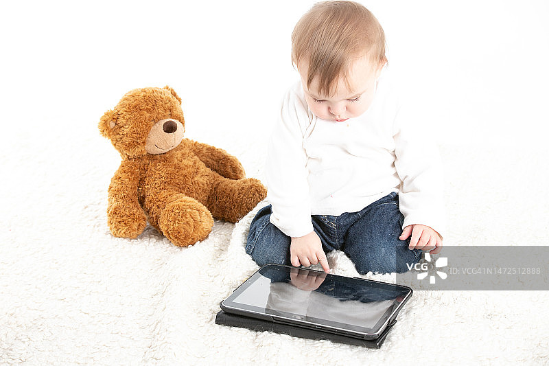 白色背景下婴儿看平板电脑影棚照图片素材