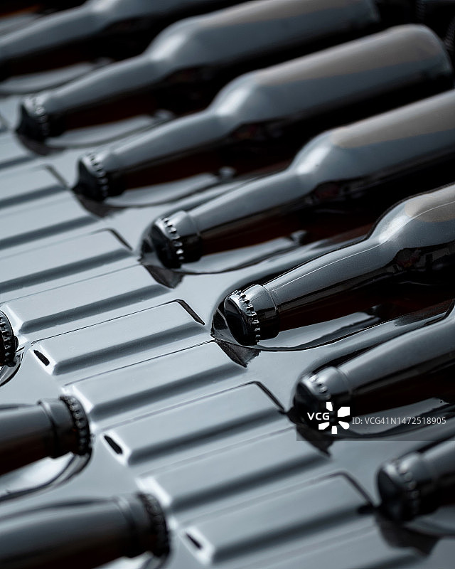 塑料包装中的黑色玻璃瓶，带有金属盖的水平放置的瓶子，饮料的生产和包装，俯视图，特写，柔焦图片素材