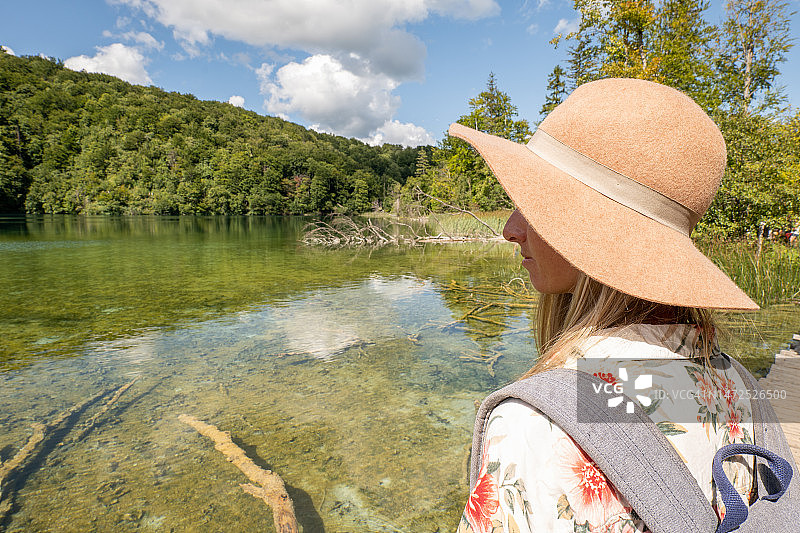 在克罗地亚的湖泊和郁郁葱葱的绿色环境中沉思的年轻女人图片素材