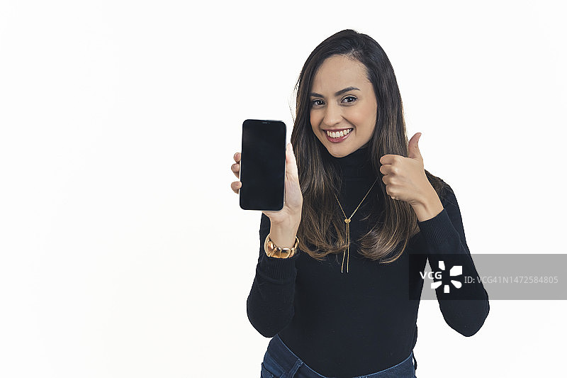 年轻女子展示智能手机空白屏幕并竖起大拇指图片素材
