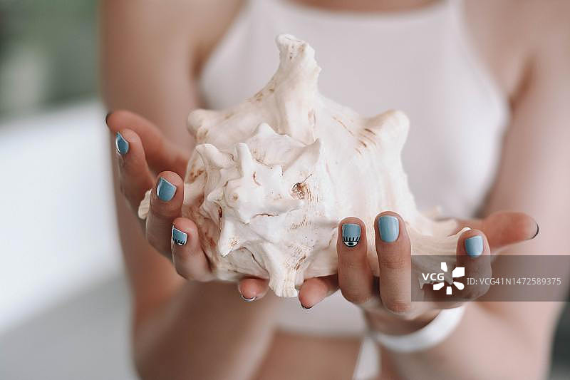 在印度尼西亚家中手持贝壳的女子（中部视角）图片素材