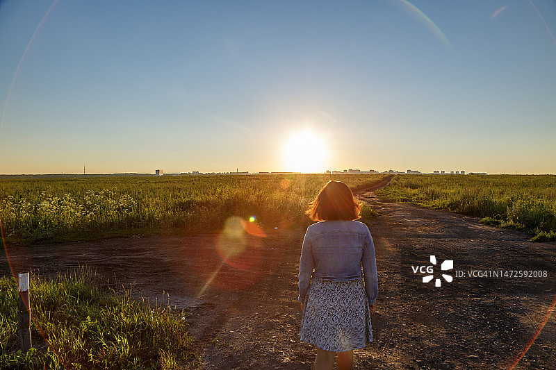 日落时分，女人站在田野上的背影，俄罗斯克麦罗沃州克麦罗沃图片素材