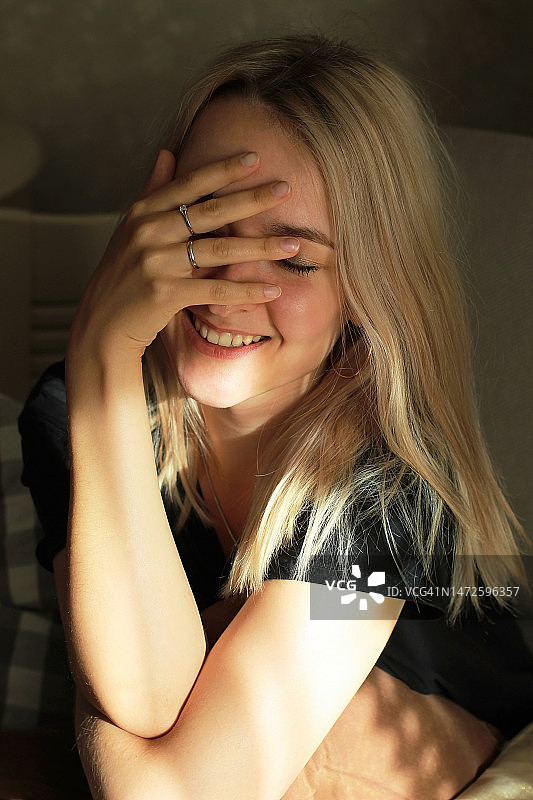 长发金发女孩害羞地用手遮住脸图片素材