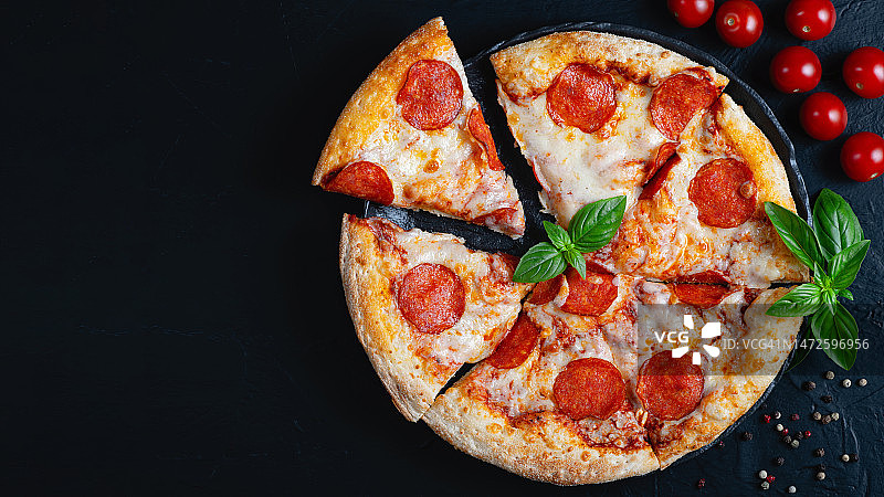 黑混凝土背景上的意大利辣香肠披萨和烹饪配料图片素材