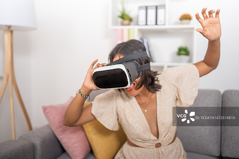 年轻女子在客厅里戴着VR眼镜图片素材