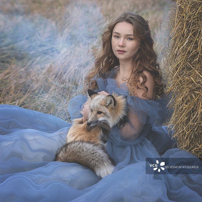 年轻女子与小狗坐在田野上，俄罗斯克麦罗沃州新库兹涅茨克图片素材