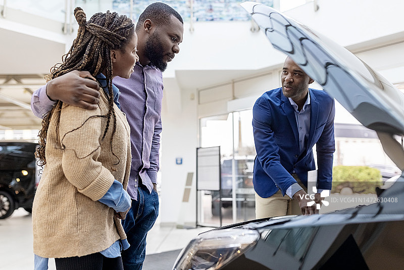 在经销商处，销售员向一对夫妇讲解汽车功能图片素材