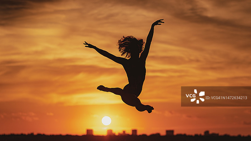 日落时分在天空跳跃的女子剪影，美国得克萨斯州达拉斯图片素材